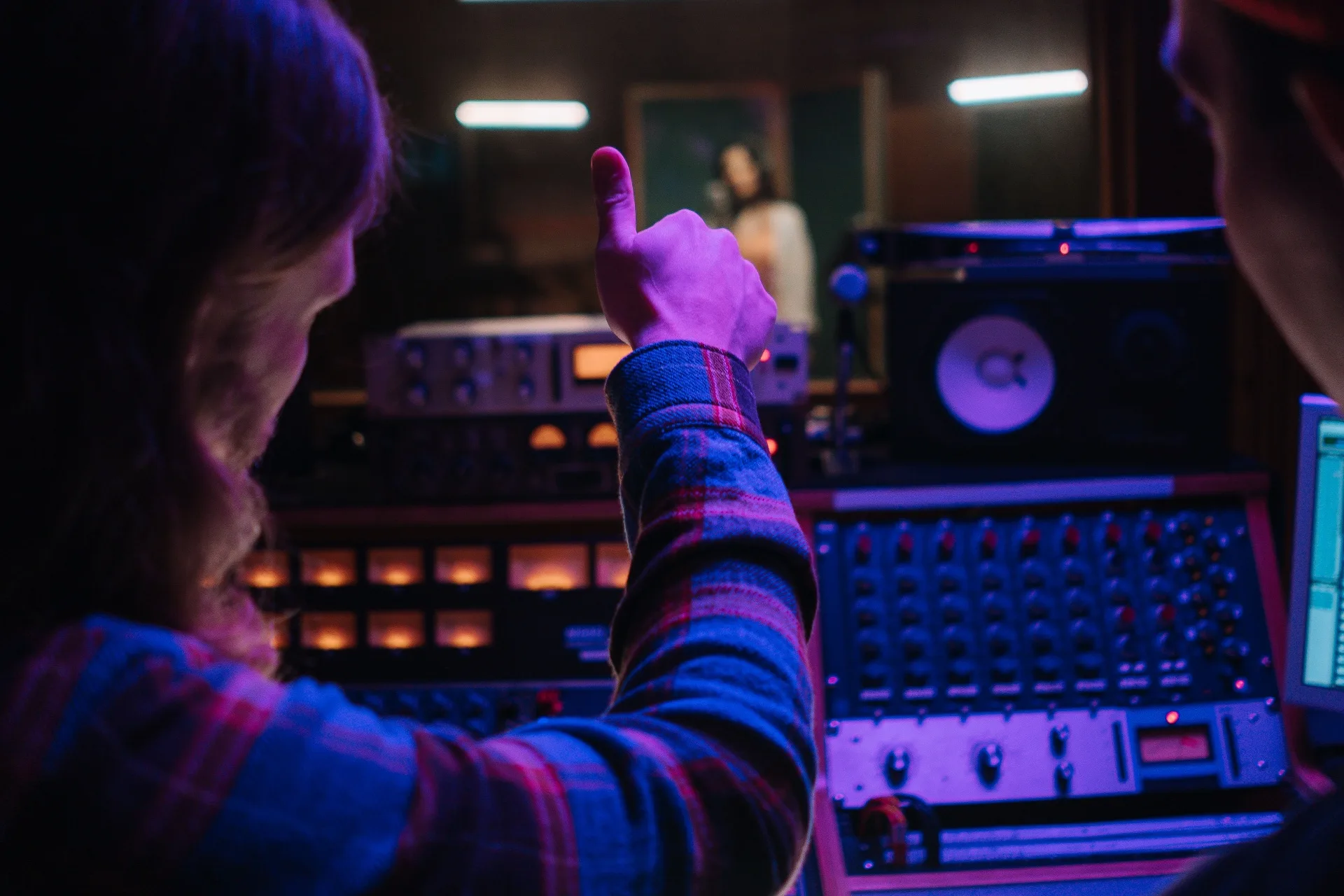 Producer giving a thumbs up in a neon-lit control room