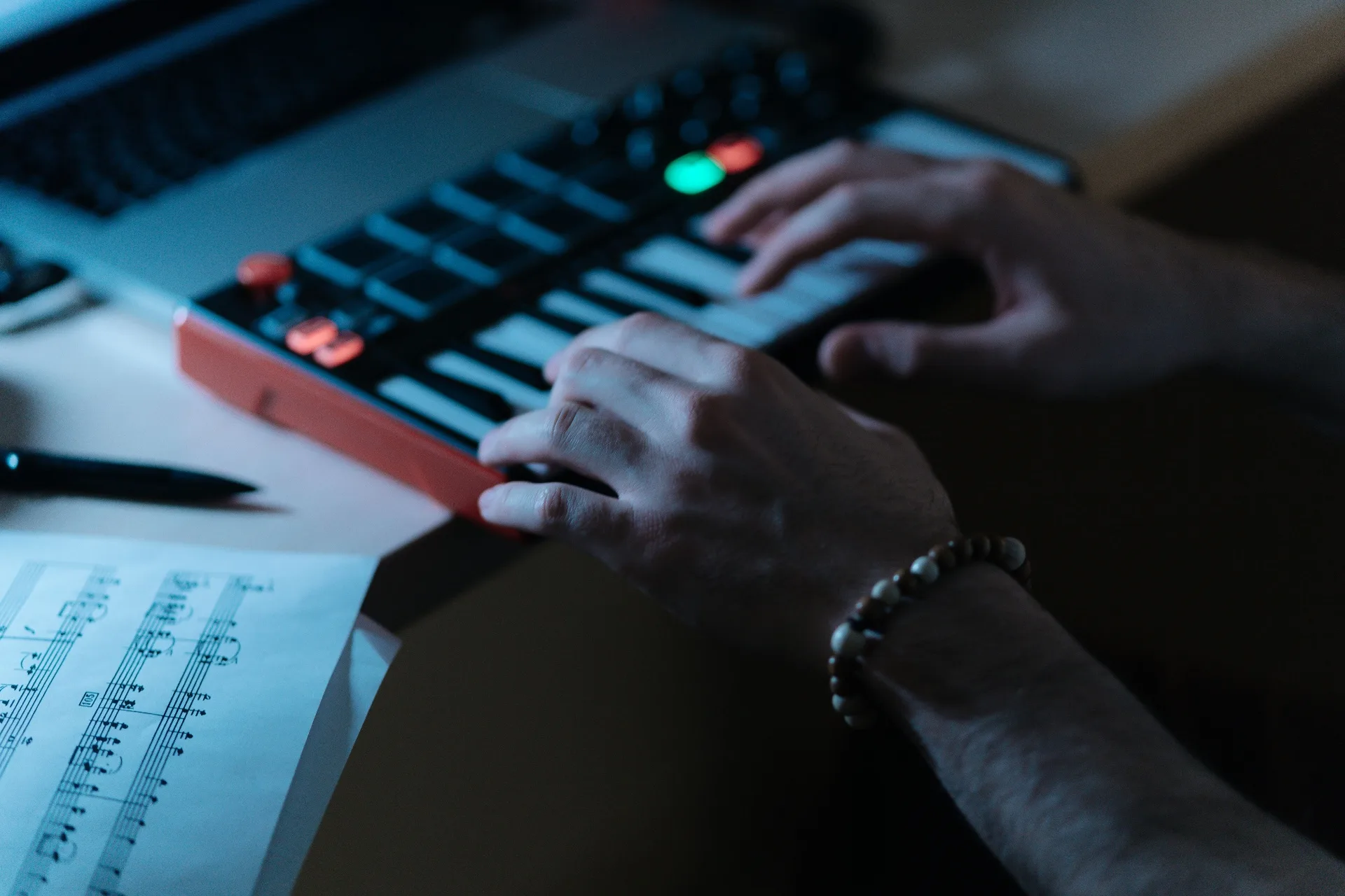 Hands playing MIDI keys with sheet music